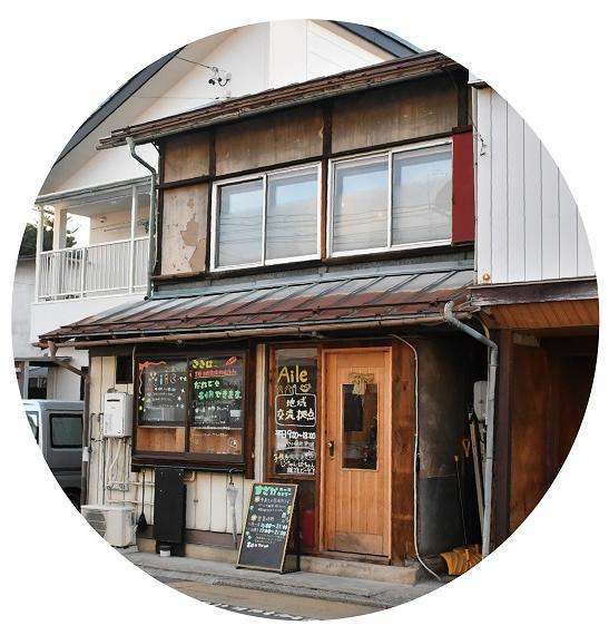 2階建ての建物の写真。1階に戸があり、戸の横の窓ガラスに「Aile地域交流拠点」の文字が書かれている。