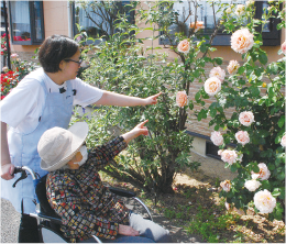 根津裕美恵さんが施設利用者とお花を見ている写真