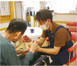 布施直人さんが施設利用者に食事を提供する写真