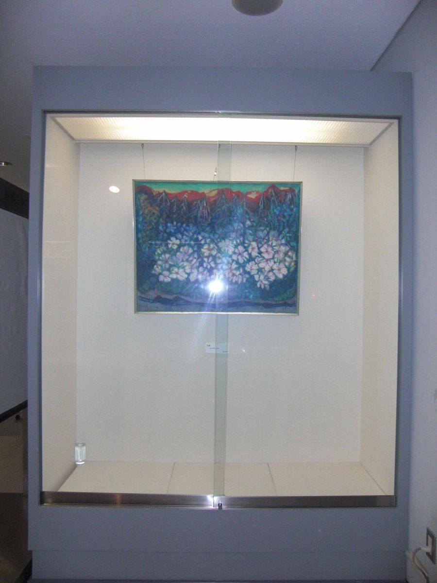 赤い山を背景に紫や白い花々が描かれた絵画が展示されている写真