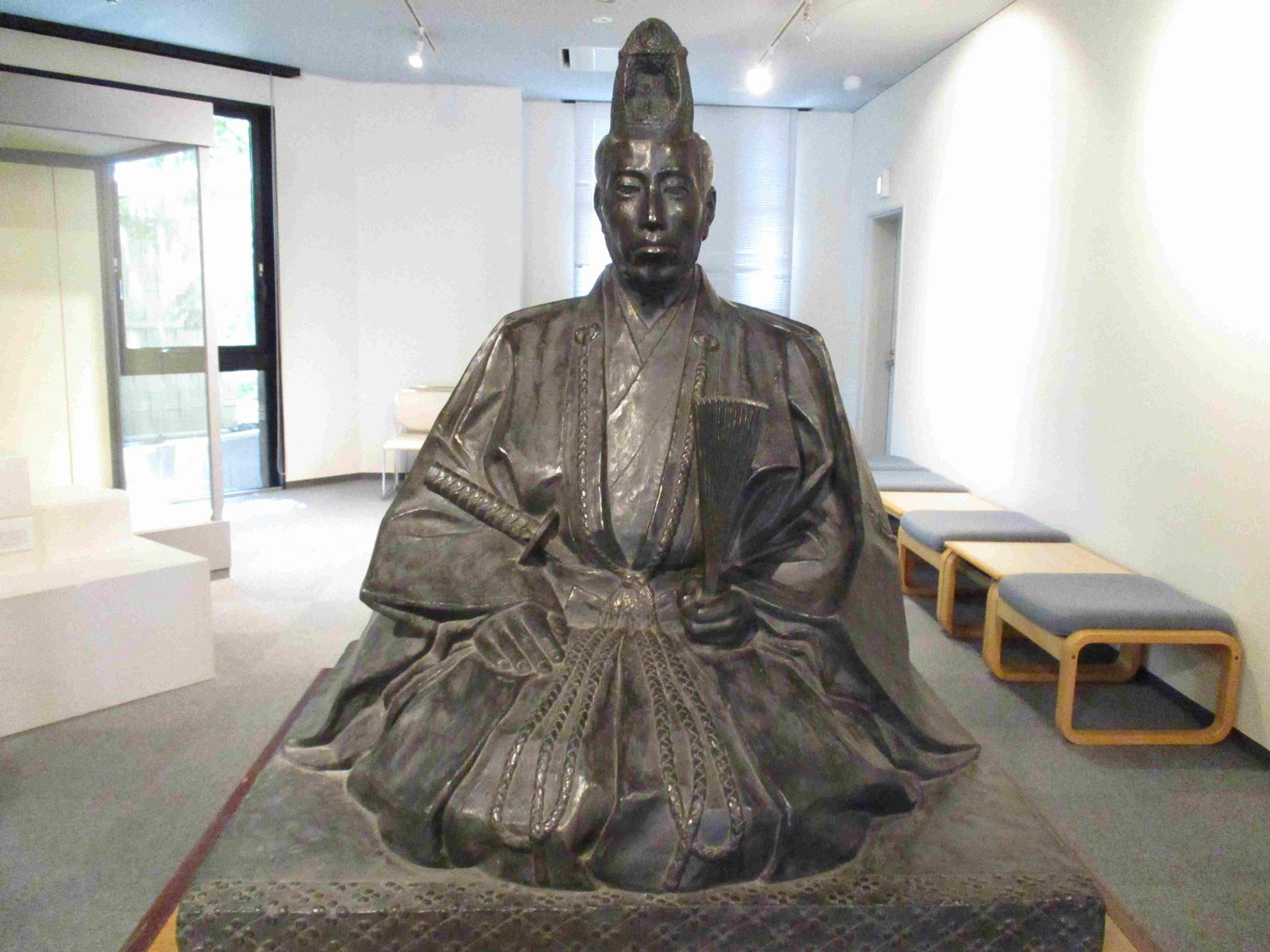 しゃくを左手に持ち、刀を腰に差し、座っている須坂藩13代藩主 堀直虎のブロンズ像の写真