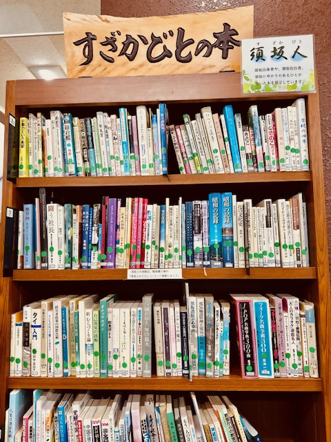 「すざかびとの本」と書かれた揮毫作品の下に並べられた本の写真