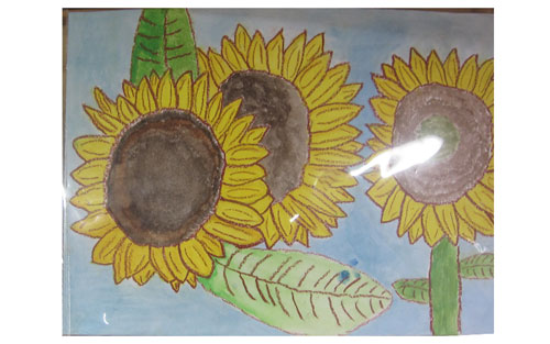 画用紙いっぱいに3輪のひまわりの花を描き、花びらや葉の筋まで丁寧に描いている図画の作品