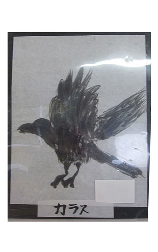 両羽を広げて飛んでいるカラスを左側から描いた墨絵の作品