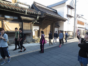 和風造りの建物や蔵が並んだ街並みを見学しながら歩いている生徒達の写真