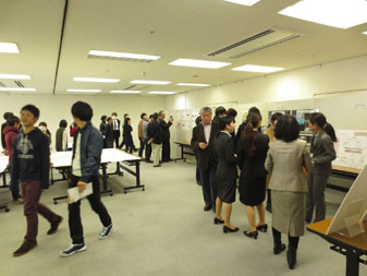 会場内に設置されたホワイトボードに展示物が貼られ、参加者たちが展示物を見ながら話している写真
