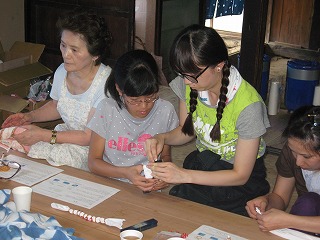 学生たちが藍染の手ぬぐい作りを教えてもらいながら作成している様子の写真