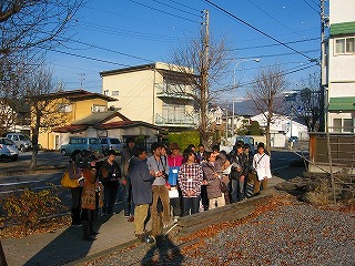 住宅街の道端で男性の説明を聞く建築学科3年生の写真