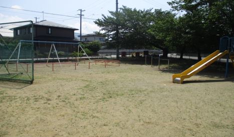 右側に木と滑り台があり、左側にブランコと柵が設置されている田の神公園の写真
