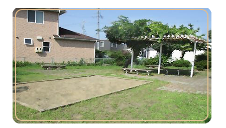 手前に長方形の砂場が設置され、その奥に木陰で休めるベンチがある蒔田公園の写真