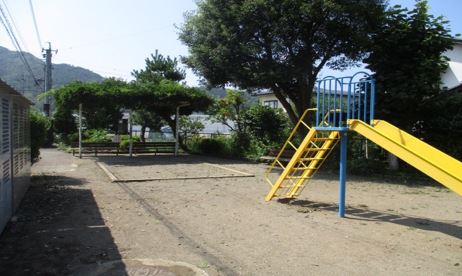 右手前に黄色と青色の滑り台があり、奥に砂場と屋根付きのベンチがある宮原公園の写真