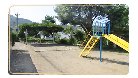右手前に黄色と青色の滑り台があり、奥に砂場と屋根付きのベンチがある宮原公園の写真