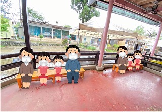 ベンチにマスク姿で座っている様子をイラスト付きで表現している写真