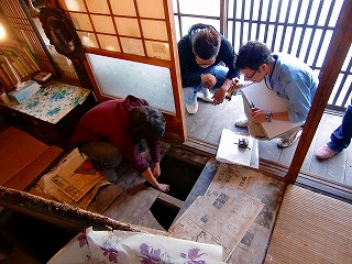 男子大学生3名が民家の床下を見ている写真