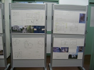 建物の図面が上下に貼られた展示用パネルが横並びに並べられている写真