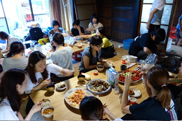 初夏合同合宿にて長机を並べ料理を食べる学生たちの写真