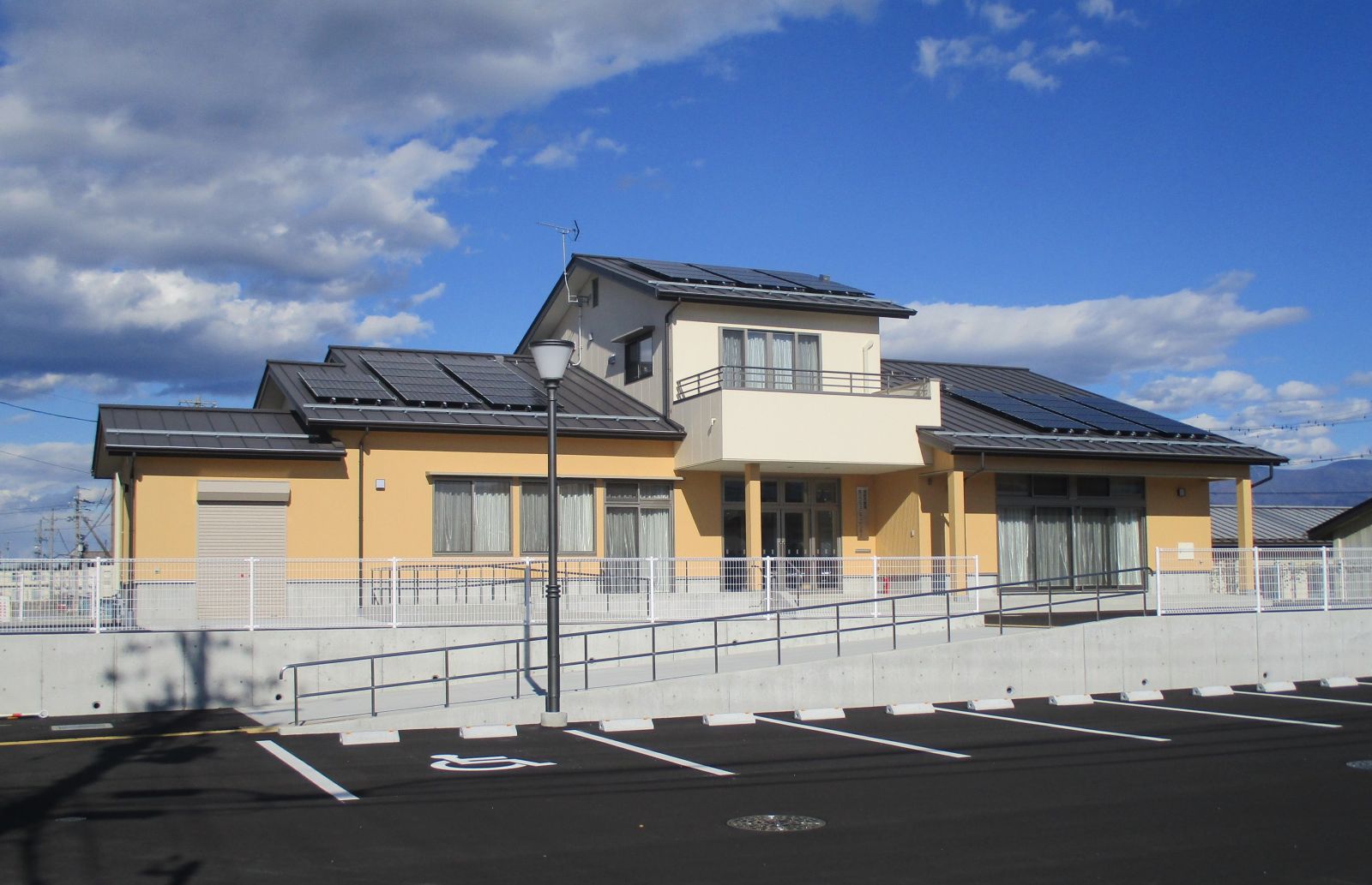 駐車場の横に建っている、クリーム色と白を基調とした外壁で2階建ての豊洲防災コミュニティセンターを写した写真