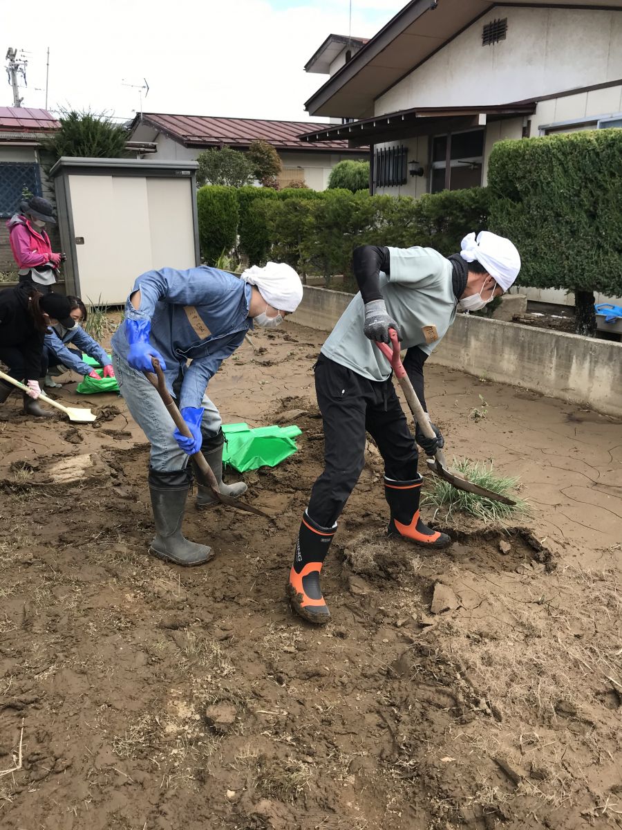 ボランティアの人が住宅敷地内の泥を撤去している写真