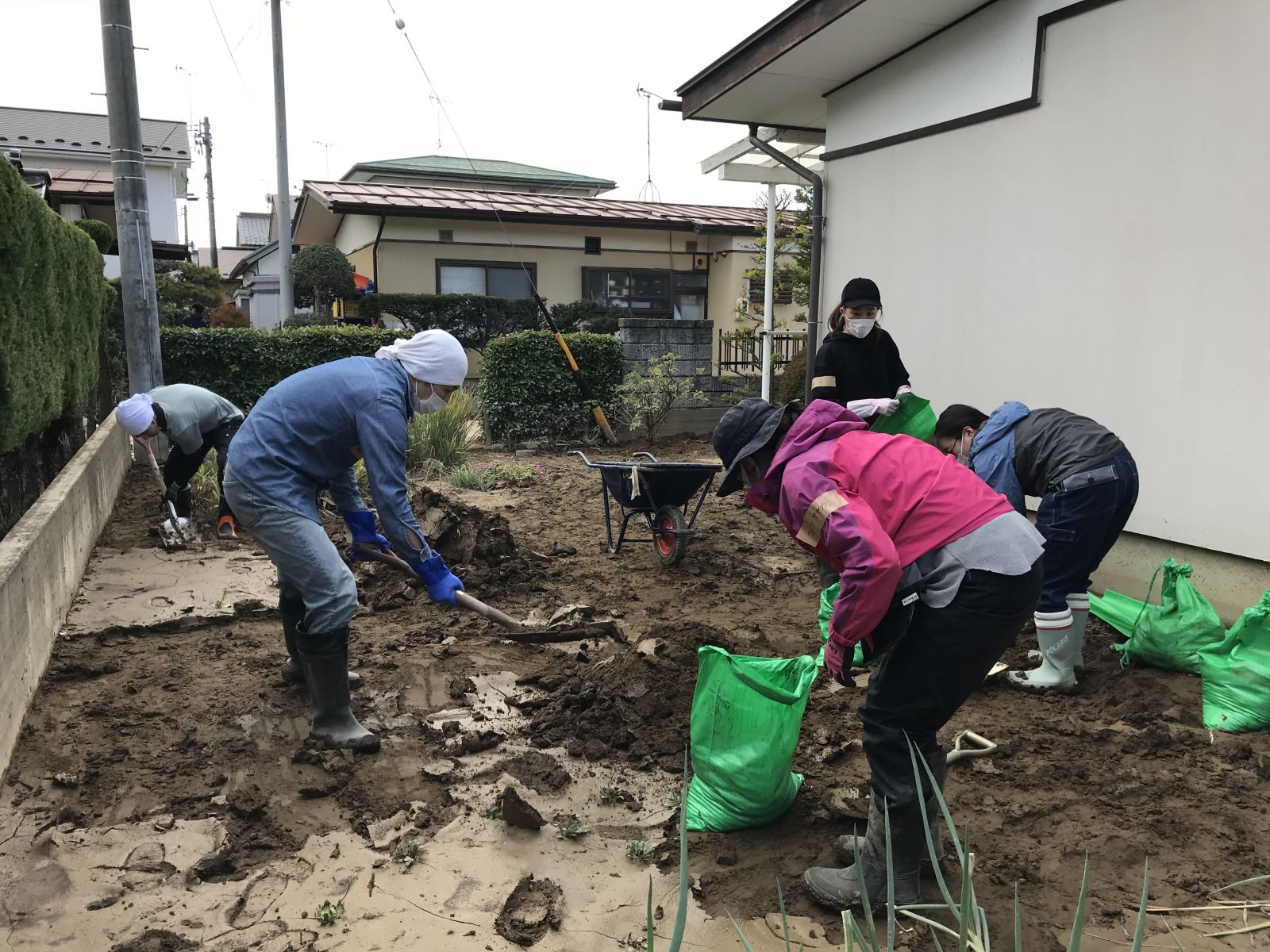 ボランティアの人が住宅敷地内の泥を撤去している写真