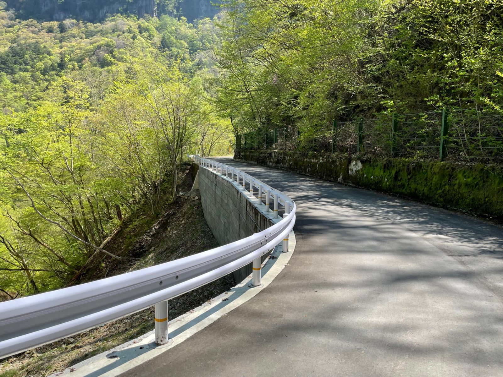 山沿いの崩落した道路のガードレールが再設置されきれいに舗装された道路の写真