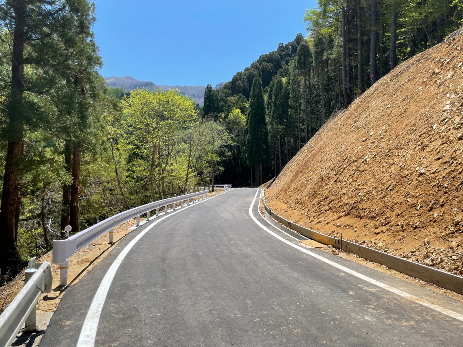 山中の崩落した道路にガードレールが設置され復旧した道路の写真
