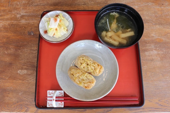 赤いお盆にのった赤色の箸とおやきとみそ汁、小鉢(おやき朝食)の写真