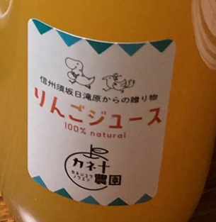 白地に信州須坂日滝原からの贈り物りんごジュース100パーセントナチュラル、カネ十農園と書かれたラベルが付いたリンゴジュースのアップ写真