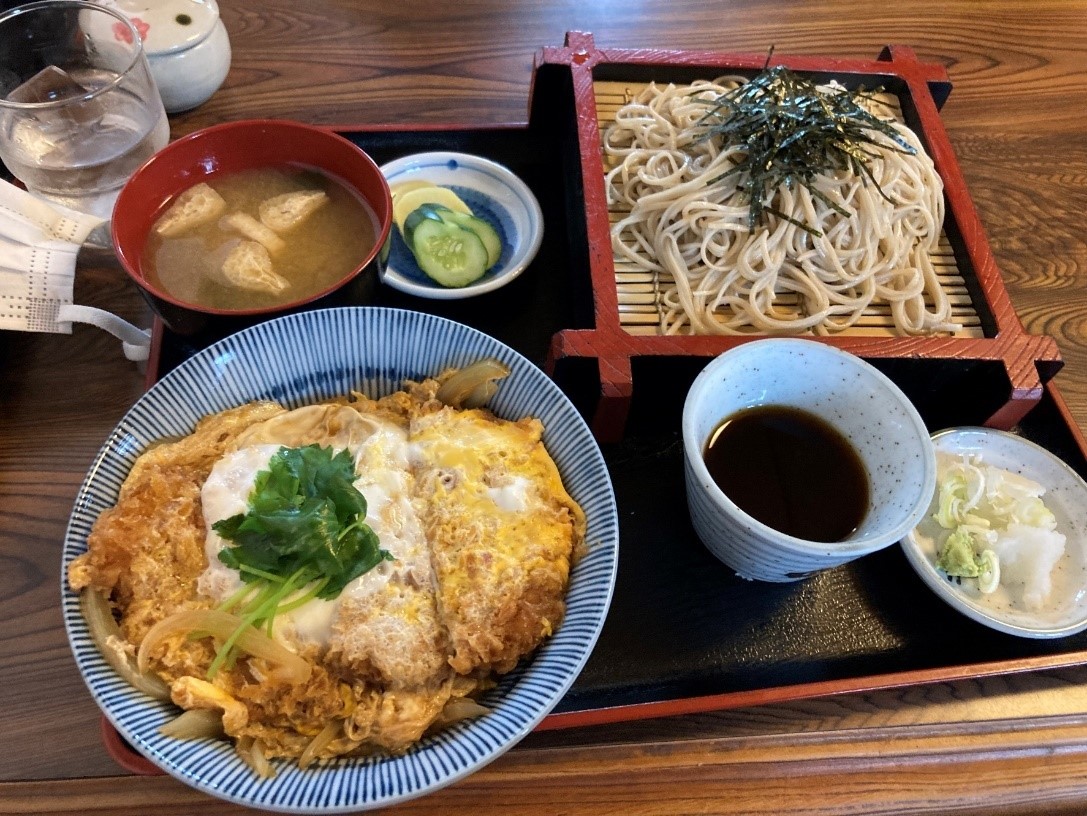 黒いお盆にのったカツ丼と蕎麦、みそ汁、お漬物の写真