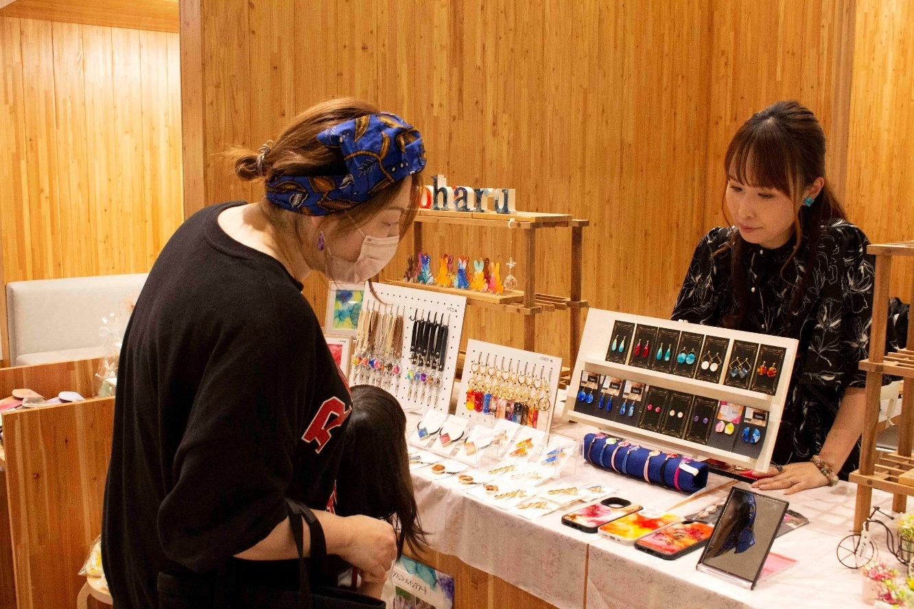 作品を見ている女性に向かい合って接客する中澤明加さんの写真
