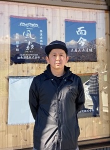 新崎酒店前で撮られた新崎 孝志さんの写真