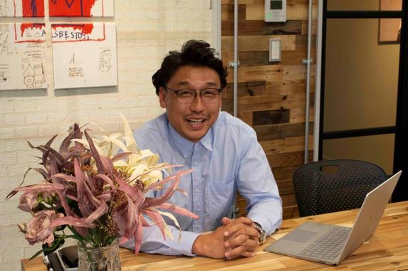 デスクに座り手を組む山崎喜彰さんの写真