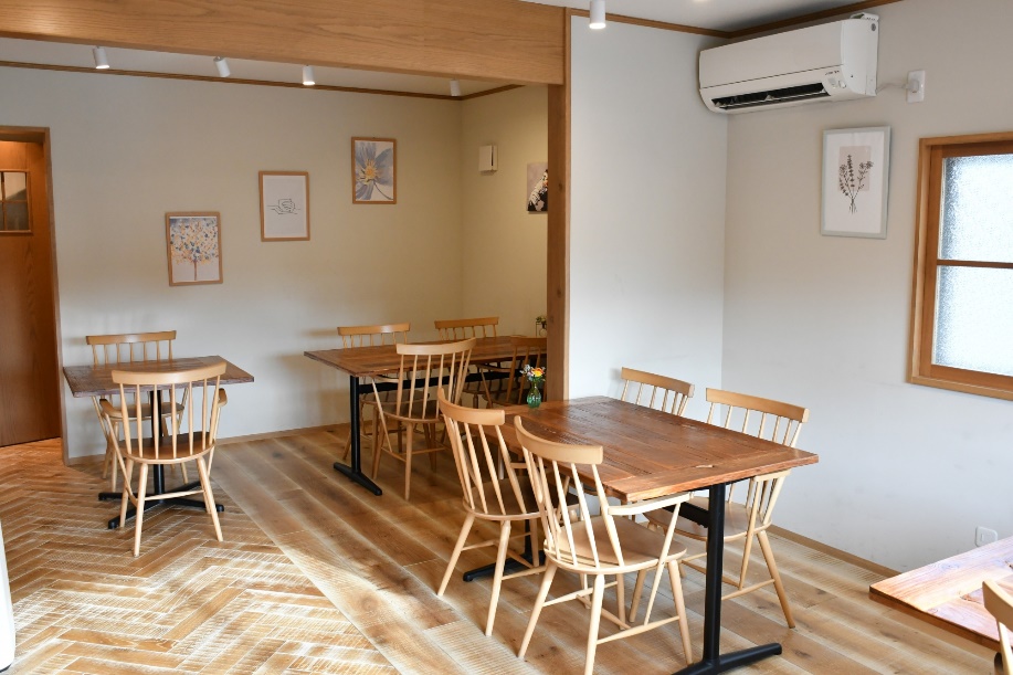 店内の写真。明るい色の木調家具で揃えられ、壁紙は白。ところどころにフレームに入った絵がかけられ、明るく温かみのある雰囲気