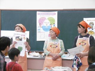 地元の旬の野菜など写真を見せながら説明をしている様子の写真