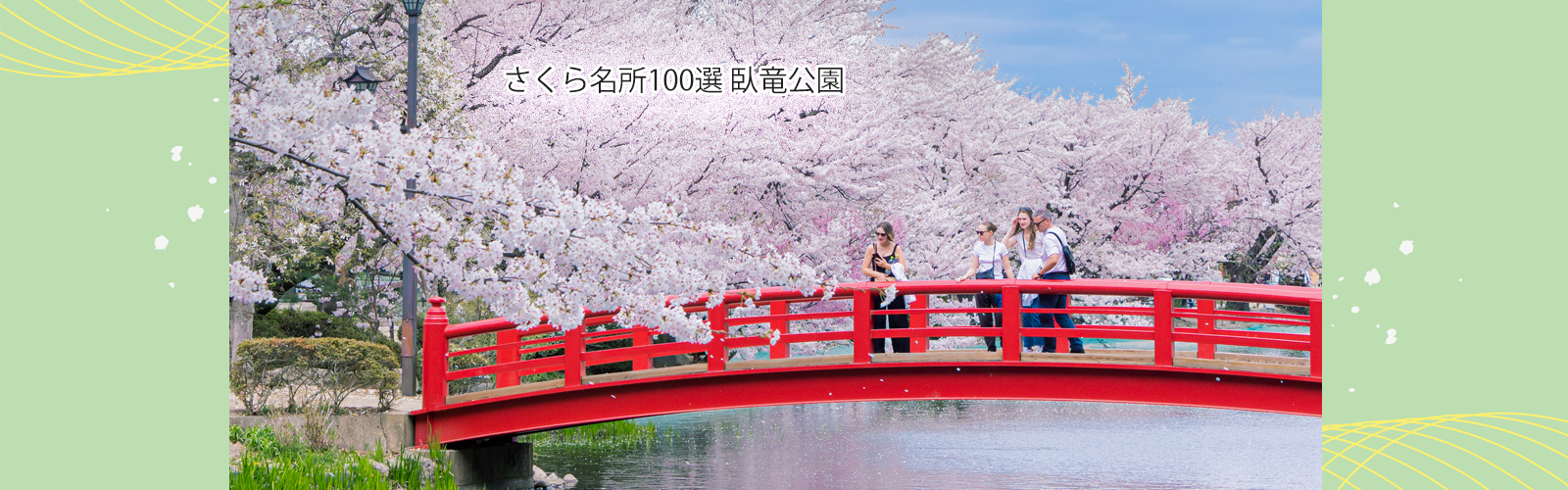 須坂市を代表する臥竜公園の写真。桜の季節、りゅうが池にかかる赤い弁天橋と、その周りに満開の桜。外国人観光客が橋の上から桜を眺めている。