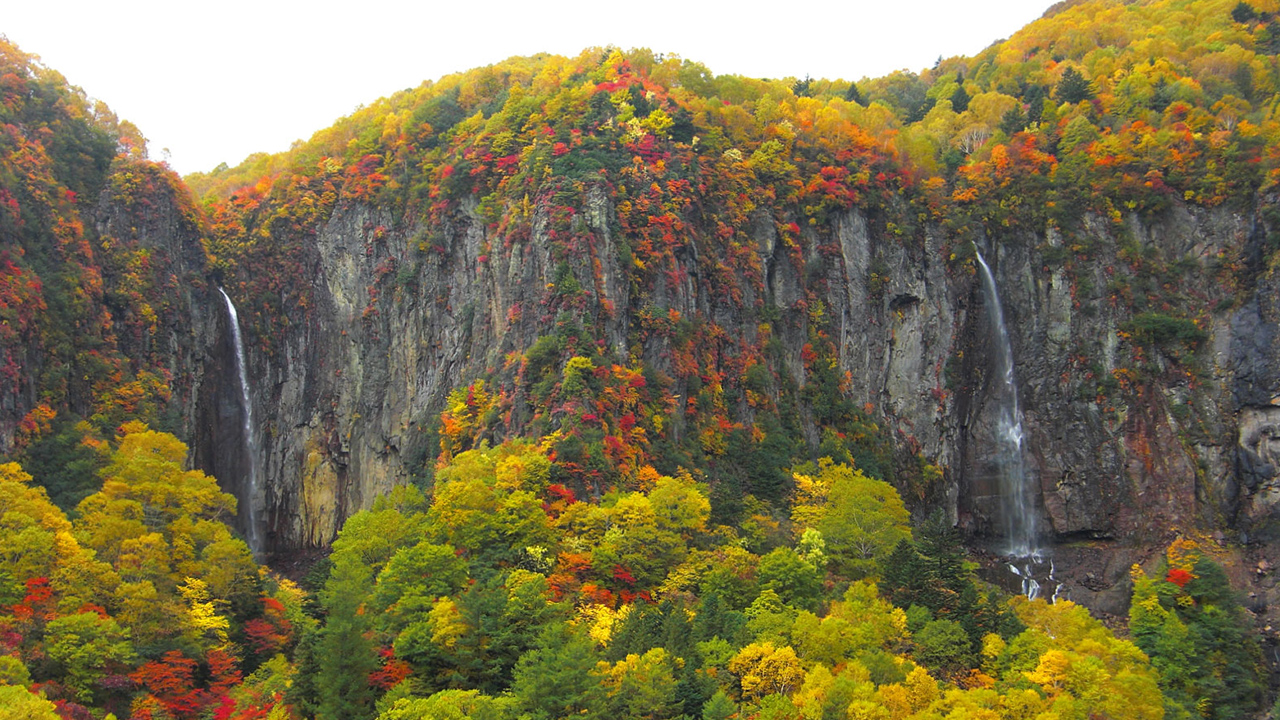 紅葉している山と谷を流れる滝