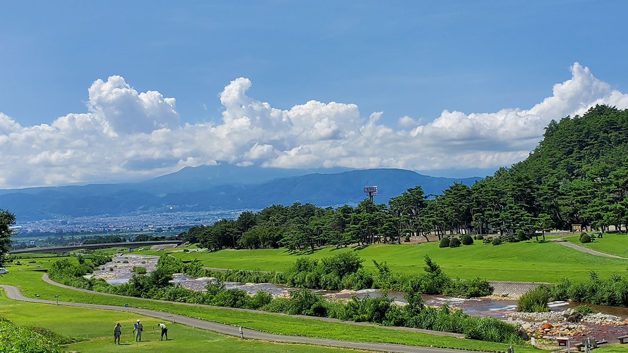 山々と街並が見える川沿いの道