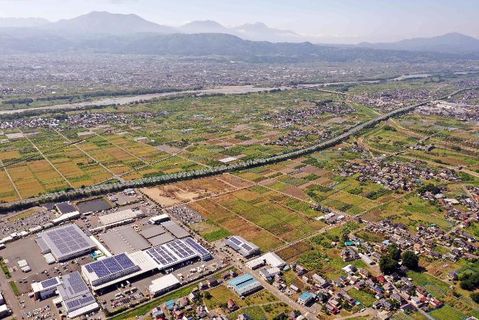 奥に千曲川が流れ、千曲川に沿って須坂インター線が伸びる。インター線の手間にに工事計画予定となる土地が広がる。