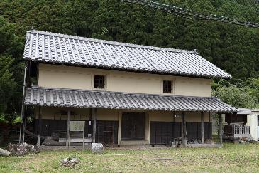 蔵の写真。白壁ではなく、木と茶色の土壁のよう。二階建てで横に長い。