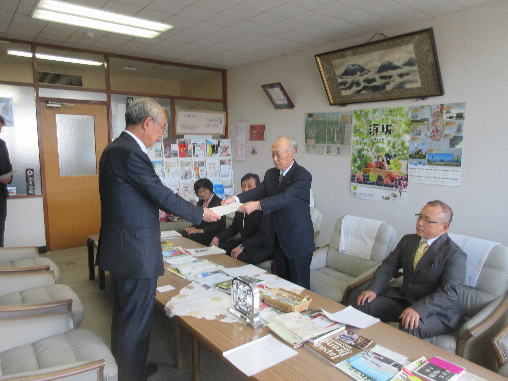 須坂市役所の応接室で、三木市長に意見書を手渡す農業委員会の皆さんの写真。