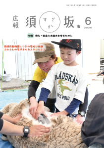 広報須坂6月号の表紙。飼育員と一緒に大きなはさみを手にした小学生の男の子が、横たわったヒツジの毛を刈っている。
