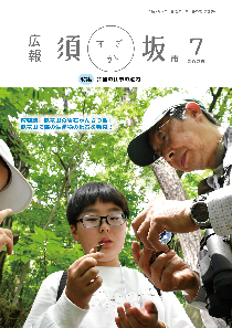 広報須坂7月号の表紙。「岩石かんさつ会で男このこと講師が発見した化石を観察している」