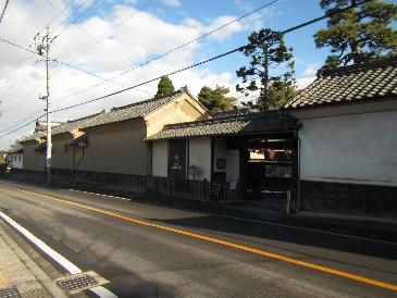 道路沿いに、大きな屋敷を囲むように続く漆喰の白壁の写真。