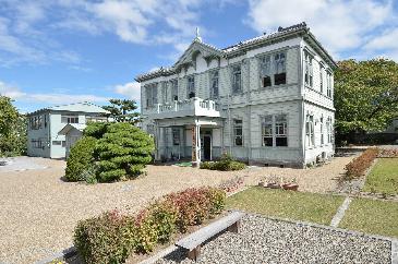 薄い緑色に塗られた、木造の洋風建築の建物の写真。