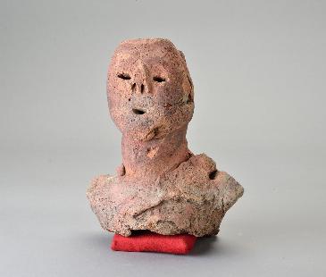 人間の方から上をかたどったと思われる埴輪の写真。髪の毛や帽子はない。なにか衣服は身に着けているようだが、華美ではない。目、鼻、口の穴かあるので人だとわかる。