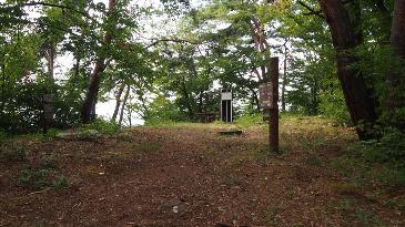 山の中、うっそうと木々が茂る頂上付近、少しだけ開けている場所の写真。