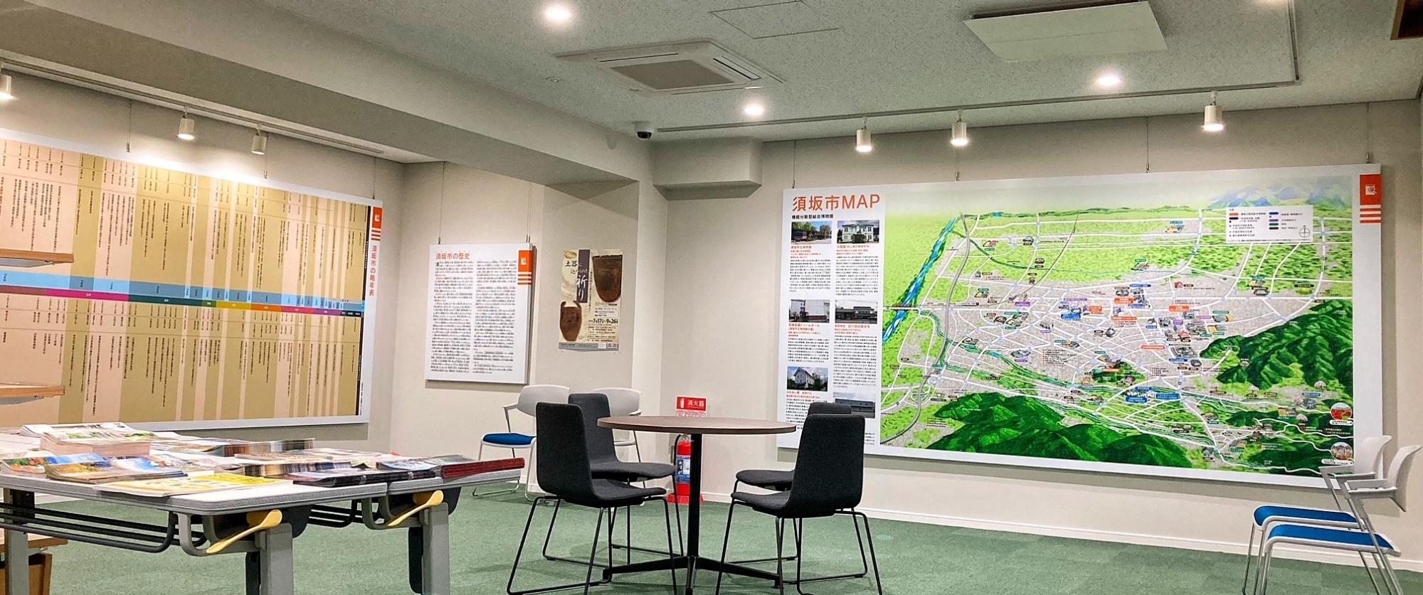 須坂市の地図が大きく壁に掲示され、テーブルや椅子、資料が並んだガイダンスルームの写真