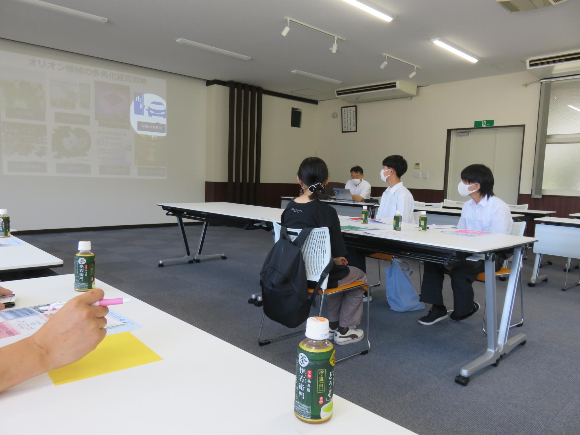 オリオン機械株式会社で説明を聞く参加者
