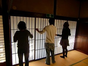 和室の障子の組子に触れる3名の大学生の後ろ姿の写真