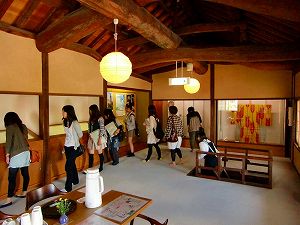 順番に1列に並び展示物を観覧している大学生たちの写真