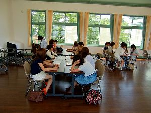 向かい合わせた長机に座り、グループワークする大学生たちの写真